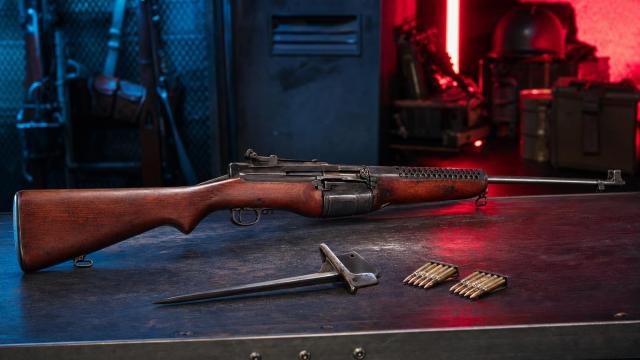 Historicky presná samonabíjacia puška Johnson M1941 na stole dobovej vojenskej dielne.