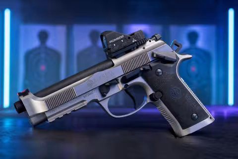 Oceľová pištoľ Beretta 92X Performance Carry Optic s kolimátorom na stole strelnice.